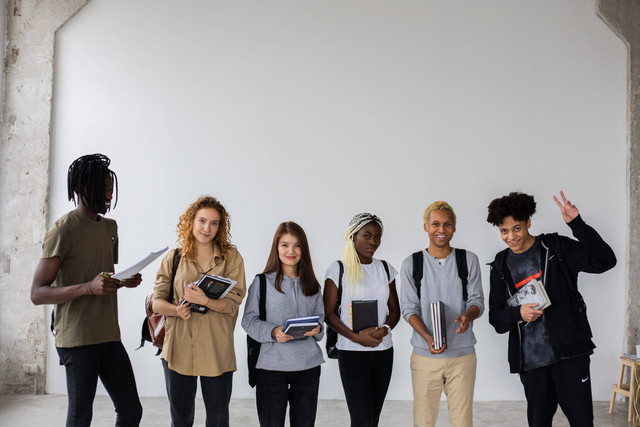 Foto: https://www.pexels.com/photo/cheerful-multiethnic-students-with-notepads-and-textbooks-together-6238109/