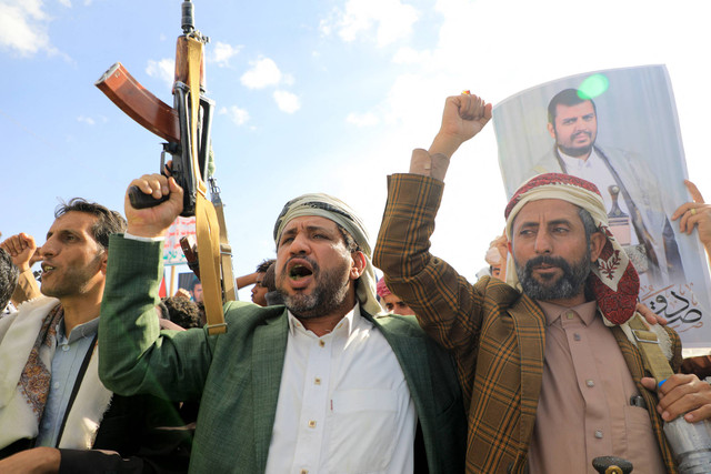Pria Yaman mengacungkan senjata mereka dan memegang potret pemimpin Houthi Abdul Malik al-Houthi selama protes solidaritas terhadap rakyat Palestina di ibu kota Yaman yang dikuasai Huthi, Sanaa pada 5 Januari 2024. Foto: Mohammed Huwais / AFP