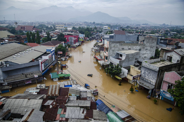 Warga berjalan melewati genangan banjir di Dayeuhkolot, Kabupaten Bandung, Jawa Barat, Jumat (12/1/2024). Foto: ANTARA FOTO/Novrian Arbi