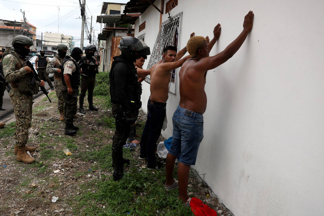 Petugas polisi memeriksa orang-orang, di tengah gelombang kekerasan yang sedang berlangsung di seluruh negara, di Guayaquil, Ekuador, Jumat (12/1/2024). Foto: Ivan Alvarado/REUTERS