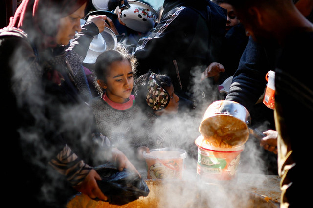 Warga Palestina menunggu untuk menerima makanan yang dimasak oleh dapur amal, di tengah kekurangan pasokan makanan, di Rafah, selatan Jalur Gaza, 16/1/2024). Foto: Ibraheem Abu Mustafa/REUTERS