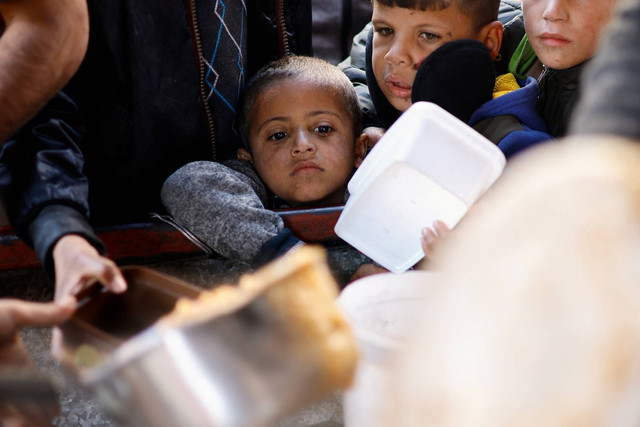 Anak-anak Palestina mengantre untuk menerima makanan yang dimasak oleh dapur amal, di tengah kekurangan pasokan makanan, di Rafah, selatan Jalur Gaza, 16/1/2024). Foto: Ibraheem Abu Mustafa/REUTERS
