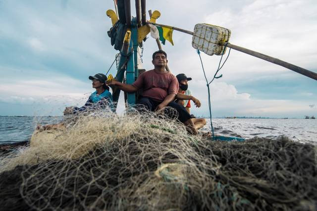 Nelayan Cilincing asal Indramayu Royani (tengah), Sukardi (kiri) dan Judi (kanan) berada di perairan Teluk Jakarta saat berlayar menuju Indramayu.  Foto: Muhammad Adimaja/ANTARA FOTO