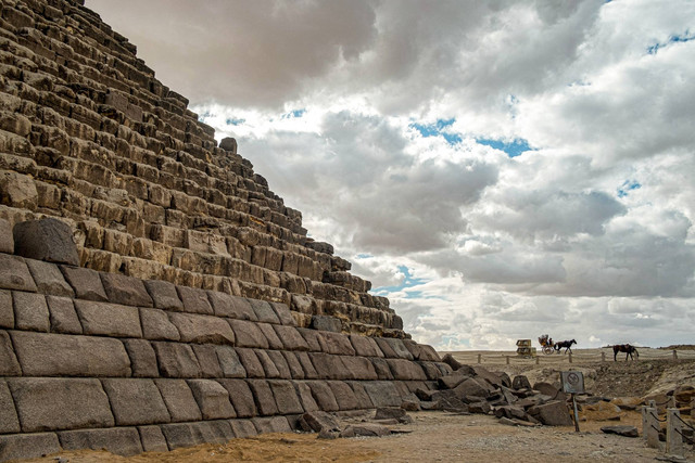 Seekor kuda menarik kereta wisata bergerak di dekat dasar Piramida Menkaure (atau Menkheres, dibangun pada abad ke-26 SM) di Pemakaman Piramida Giza, sebelah barat Kairo, Mesir pada Senin (29/1/2024). Foto: Khaled Desouki/AFP