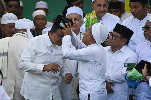 Salah satu ulama mengenakan peci tanda dukungan untuk capres-cawapres nomor urut 1 Anies Baswedan (kiri) dan Muhaimin Iskandar (kanan) saat berkampanye di Lapangan Pondok Pesantren Gunung Sari, Pamekasan, Jawa Timur, Rabu (31/1/2024). Foto: Aditya Pradana Putra/ANTARA FOTO