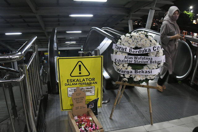 Seorang penumpang kereta melakukan aksi di depan bunga duka cita atas rusaknya satu eskalator di Stasiun Bekasi, Jawa Barat, Rabu (31/1/2024). Foto: ANTARA FOTO/ Fakhri Hermansyah