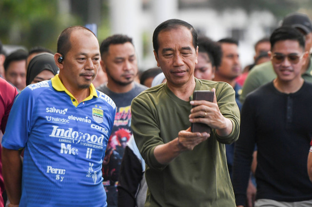 Presiden Joko Widodo (tengah) didampingi putranya Kaesang Pangarep (kanan) berswafoto dengan warga saat berjalan kaki di Lapangan Gasibu, Bandung, Jawa Barat, Minggu (4/2/2024). Foto: Hafidz Mubarak A/Antara Foto