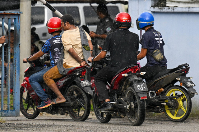 Pihak berwenang Malaysia mengawal seorang tahanan yang diborgol (kedua dari kiri) ke pusat penahanan imigrasi di Bidor di negara bagian Perak utara Malaysia pada tanggal 2 Februari 2024. Foto: Mohd Rasfan/AFP