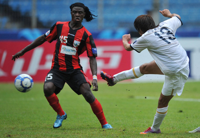 Pemain Kashima Antlers Jepang Kohrogi Shinzoh (kanan) menendang bola melewati pemain Indonesia Persipura Jayapura Bio Paulin Pierre (kanan) untuk mencetak gol kedua dalam pertandingan sepak bola liga juara AFC di Stadion Bung Karno di Jakarta. Foto: Bay Ismoyo/AFP
