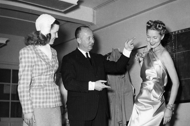 Desainer Prancis Christian Dior, di studio fesyennya, melakukan beberapa penyesuaian pada seorang model. Foto: STAF/INTERCONTINENTALE/AFP