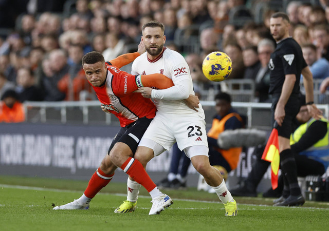 Carlton Morris duel dengan Luke Shaw saat laga Luton Town vs Manchester United (MU) dalam pekan ke-25 Liga Inggris 2023/24 di Stadion Kenilworth Road pada Minggu (18/2) malam WIB. Foto: Action Images via Reuters/Peter Cziborra