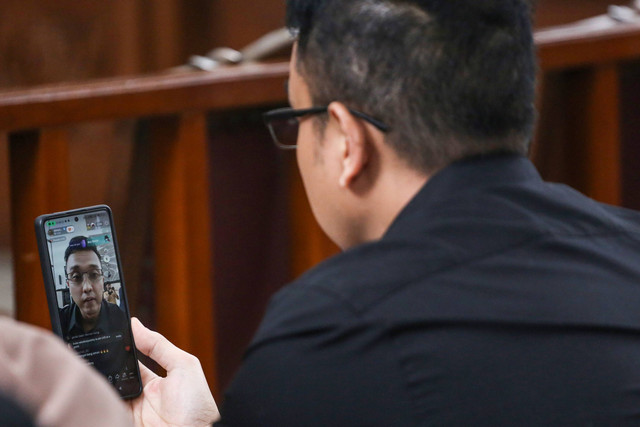 Pemohon Aiman Witjaksono melakukan siaran langsung melalui sosial media saat menghadiri sidang perdana praperadilan di Pengadilan Negeri Jakarta Selatan, Jakarta, Senin (19/2/2024). Foto: Asprilla Dwi Adha/ANTARA FOTO