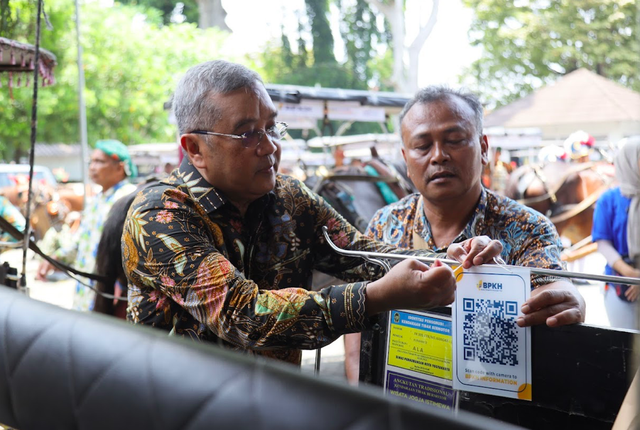 Anggota Bidang Kesekretariatan Badan dan Kemaslahatan BPKH Amri Yusuf memasang QR Code di kursi penumpang andong di Jogja. Foto: Dok. Istimewa