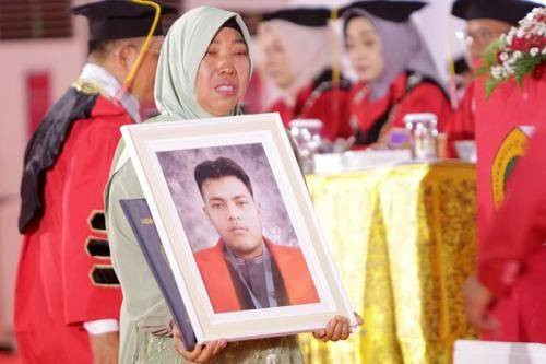 Tumini saat menggantikan mendiang putranya wisuda.