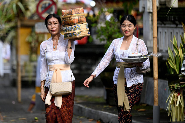 Wanita Bali membawa persembahan untuk didoakan merayakan Hari Raya Kuningan di Pura Sakenan, Denpasar, Bali, Sabtu (9/3/2024). Foto: Sonny Tumbelaka/AFP