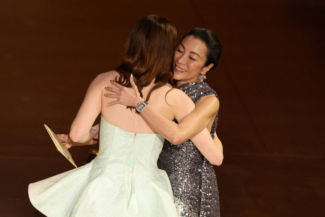 Michelle Yeoh berpelukan dengan Emma Stone pada Oscar 2024 di Academy Awards ke-96, Hollywood, Los Angeles, California, Amerika Serikat, Minggu (10/3/2024). Foto: Mike Blake/REUTERS