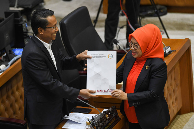 Ketua Baleg DPR Supratman Andi Agtas (kiri) menerima berkas pendapat dan pandangan dari anggota Dewan Perwakilan Daerah (DPD) Sylviana Murni (kanan) saat rapat kerja mengenai kelanjutan Rancangan Undang-Undang Daerah Khusus Jakarta (RUU DKJ). Foto: Aditya Pradana Putra/Antara Foto