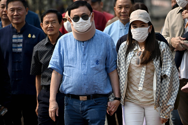 Mantan perdana menteri Thailand Thaksin Shinawatra (tengah) berjalan bersama putrinya Paetongtarn Shinawatra (kanan) saat mereka mengunjungi Royal Park Rajapruek di Chiang Mai pada 14 Maret 2024. Foto: Lillian Suwanrumpha / AFP