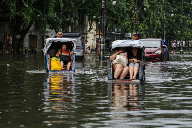Warga menaiki becak menembus banjir di Semarang, Kamis (14/3/2024). Foto: Makna Zaezar/Antara Foto