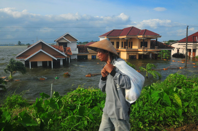 Warga melintas di dekat rumah yang terendam banjir di Dusun Goleng, Pasuruan Lor, Kudus, Sabtu (16/3/2024). Foto: Yusuf Nugroho/ANTARA FOTO