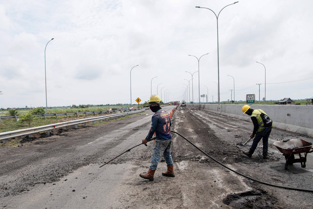 Pekerja dibantu alat berat menyelesaikan pengaspalan Jalan Tol Trans Sumatera ruas Kayu Agung-Palembang (Kapal) di Jejawi, Ogan Komering Ilir (OKI), Sumatera Selatan, Senin (27/3/2023). Foto: Nova Wahyudi/ANTARA FOTO