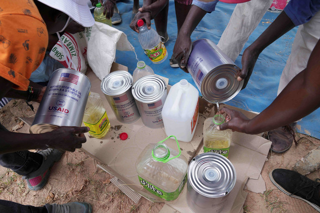 Perempuan berbagi minyak goreng saat pembagian makanan di distrik Mangwe di barat daya Zimbabwe, Jumat, (22/3/2024) Foto: Tsvangirayi Mukwazhi/AP Photo