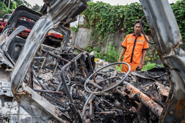 Seorang petugas melihat bangkai kendaraan pascakecelakaan di Tol Jakarta-Cikampek KM 58 di Pool Derek Cikopo, Purwakarta, Jawa Barat, Senin (8/4/2024). Foto: Bayu Pratama S/ANTARA FOTO