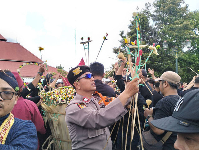 Seorang Polisi sedang berjaga dan membantu warga untuk mendapatkan isi gunungan. Foto: M wulan