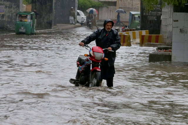 Seorang warga Pakistan dengan sepedanya mengarungi jalan yang terendam banjir akibat hujan lebat di Peshawar, Pakistan, Senin, (15/4/2024) Foto: Muhammad Sajjad/AP