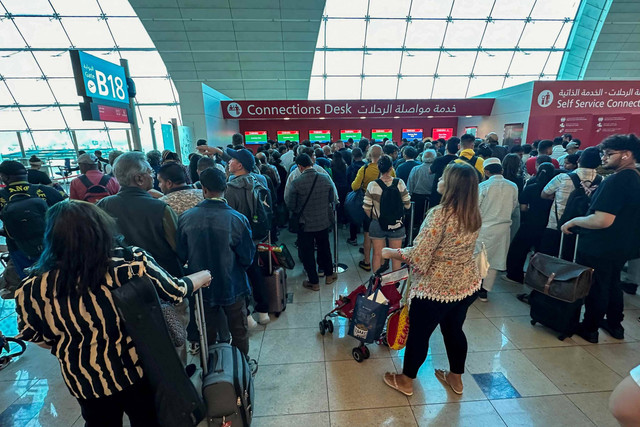 Penumpang mengantei di meja koneksi penerbangan di Bandara Internasional Dubai di Dubai (17/4/2024). Bandara belum pulih akibat hujan deras yang memicu banjir. Foto: AFP