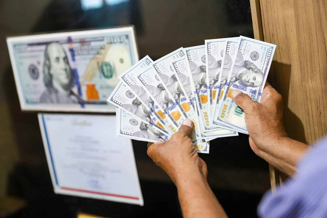 Petugas menujukkan pecahan mata uang Dolar di salah satu gerai penukaran mata uang di kawasan Kemang, Jakarta, Rabu (17/4/2024). Foto: Iqbal Firdaus/kumparan
