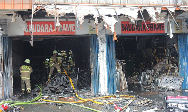 Petugas pemadam kebakaran melakukan pendinginan ruko Saudara Frame dan Galery yang terbakar di Jalan Mampang Prapatan, Jakarta, Jumat (19/4/2024). Foto: Reno Esnir/Antara Foto