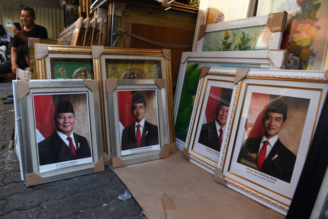 Pedagang menata foto pasangan Prabowo-Gibran sebagai Presiden dan Wakil Presiden 2024-2029 di kawasan Pasar Baru, Jakarta, Selasa (23/4/2024). Foto: Muhammad Adimaja/ANTARA FOTO