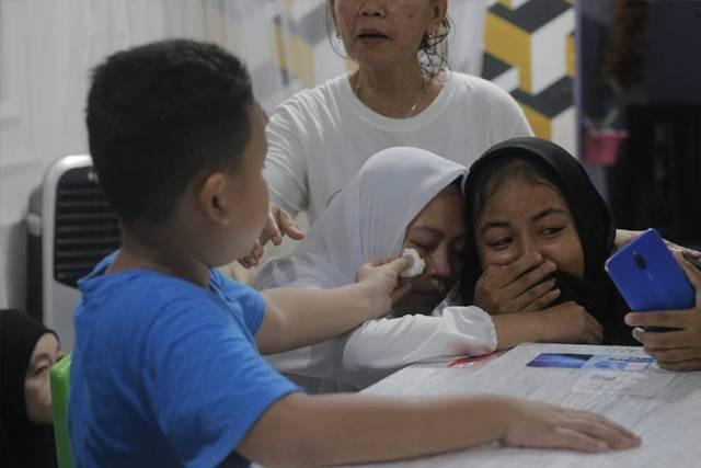Momen haru saat Adam (7), anak sulung Brigadir Ridhal Ali Tomi mengelap air mata ibunya yang tak berhenti menangis di depan jenazah suaminya. (foto: febry kodongan/manadobacirita)