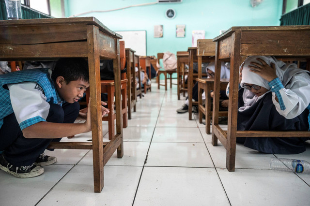 Pelajar berlindung di bawah meja saat simulasi mitigasi bencana di MTs Negeri 9 Jakarta, Johar Baru, Jakarta Pusat, Senin (29/4/2024). Foto: Aprillio Akbar/ANTARA FOTO