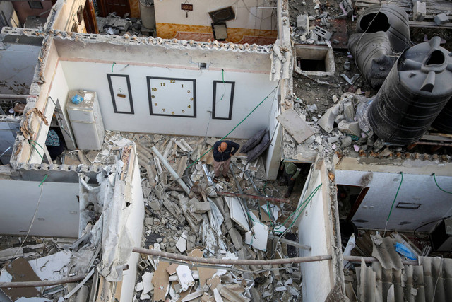 Warga Palestina memeriksa sebuah rumah yang rusak akibat serangan Israel, di tengah konflik yang sedang berlangsung antara Israel dan kelompok Islam Palestina Hamas, di Rafah, di selatan Jalur Gaza. Foto: Hatem Khaled/REUTERS