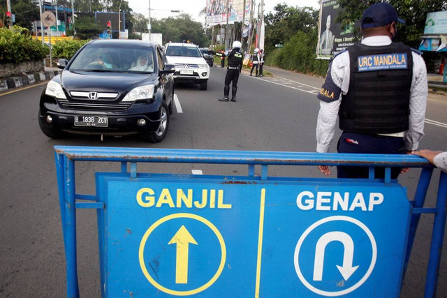 Petugas Sat Lantas Polres Bogor dan petugas Dishub Kabupaten Bogor mengarahkan kendaraan wisatawan saat penyekatan kendaraan nomor polisi ganjil genap di jalur wisata Puncak, Gadog, Kabupaten Bogor, Jawa Barat, Minggu (22/1/2023). Foto: Yulius Satria Wijaya/ANTARA FOTO