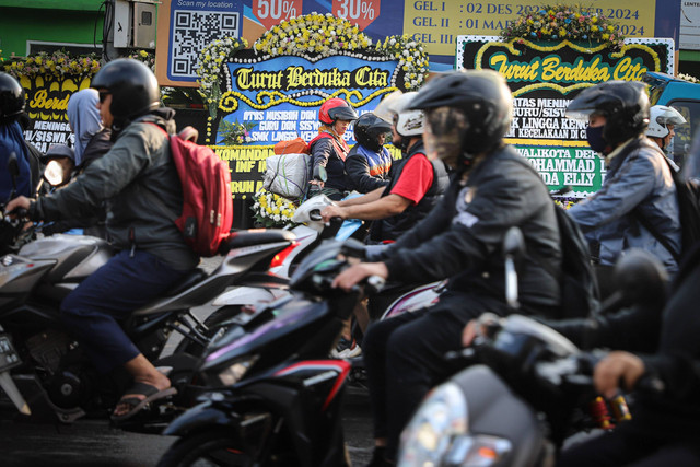 Kendaraan melintasi karangan bunga korban kecelakaan bus Ciater di SMK Lingga Kencana, Depok, Senin (13/5/2024). Foto: Iqbal Firdaus/kumparan