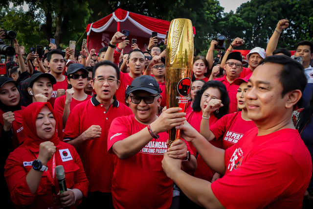 Sekjen PDIP Hasto Kristiyanto berlari sambil memegang obor bersama rombongan pembawa 'Obor Api Perjuangan' di Kemayoran, Jakarta, Kamis (23/5/2024). Foto: Jamal Ramadhan/kumparan