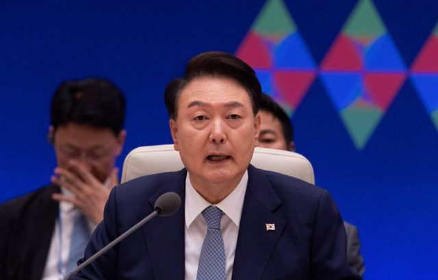 Presiden Korea Selatan Yoon Suk Yeol berbicara dengan Perdana Menteri Jepang Fumio Kishida dan Perdana Menteri Tiongkok Li Qiang (keduanya tidak digambarkan) selama pertemuan puncak trilateral mereka di Blue House di Seoul, Korea Selatan (27/5/2024). Foto: JEON HEON-KYUN/Pool via REUTERS