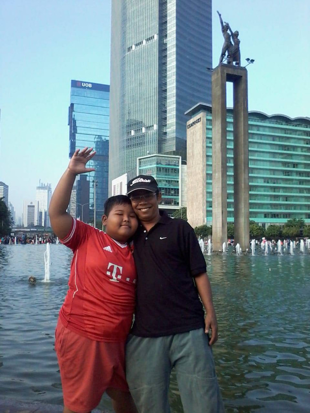 Seorang ayah sedang berfoto bersama anaknya di bundaran Hi, Jakarta Pusat. (Foto : Ahmad Rizky Pratama)