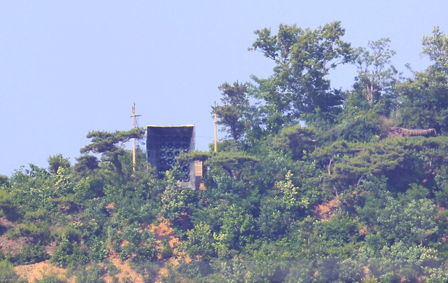 Sebuah fasilitas (atas C) yang diyakini sebagai pengeras suara Korea Utara terlihat di puncak bukit di Korea Utara dilihat dari Pulau Ganghwa Korea Selatan dekat Zona Demiliterisasi (DMZ) yang membagi kedua Korea, pada 11 Jumi 2024. Foto: YONHAP / AFP