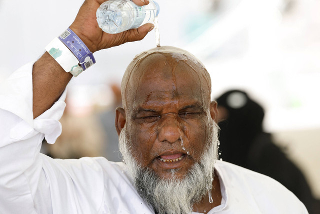 Seorang jamaah haji menuangkan air ke kepalanya untuk mendinginkan diri dari panas, saat ia mengikuti ibadah di Mina, Arab Saudi, 17 Juni 2024.  Foto: REUTERS/Mohammed Torokman