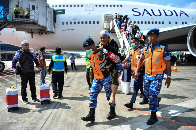 Prajurit TNI AU Sri Mulyono Herlambang menggendong jemaah haji kelompok terbang (kloter) pertama debarkasi Palembang setibanya di Bandara Sultan Mahmud Baddarudin (SMB) II Palembang, Sumatera Selatan, Minggu (23/6/2024).  Foto: Nova Wahyudi/ANTARA FOTO
