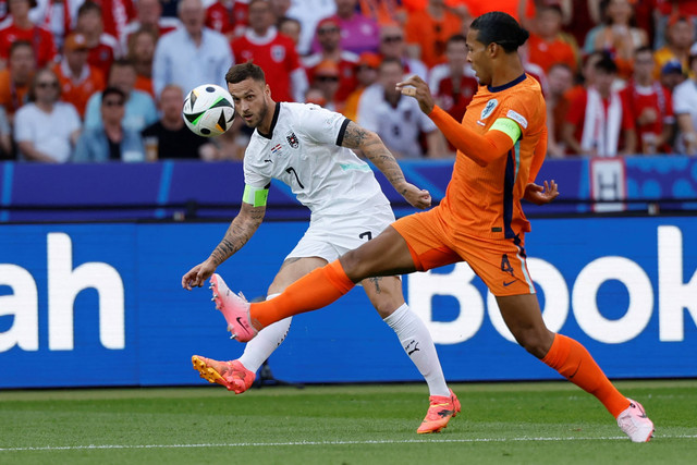 Pemain Timnas Belanda Virgil van Dijk berebut bola dengan pemain Timnas Austria Marko Arnautovic pada pertandingan Grup D Piala Eropa 2024 di Olympiastadion di Berlin, Jerman, Selasa (25/6/2024). Foto: Odd Andersen/AFP
