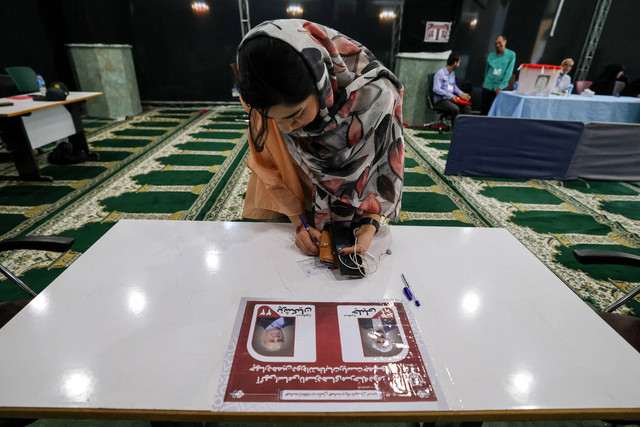 Seorang wanita Iran bersiap untuk memberikan suaranya di tempat pemungutan suara di Teheran pada 5 Juli 2024. Foto: ATTA KENARE / AFP