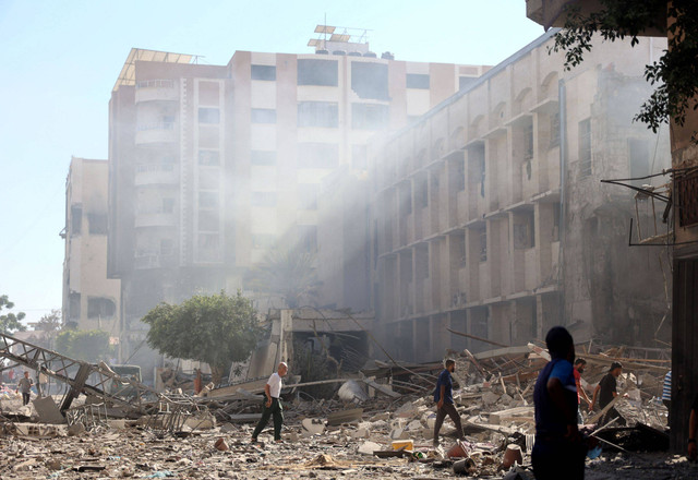 Warga Palestina berdiri di dekat reruntuhan Sekolah Keluarga Suci Patriarkat Latin usai terkena serangan militer Israel di Kota Gaza, Minggu (7/7/2024). Foto: Omar AL-QATTAA / AFP