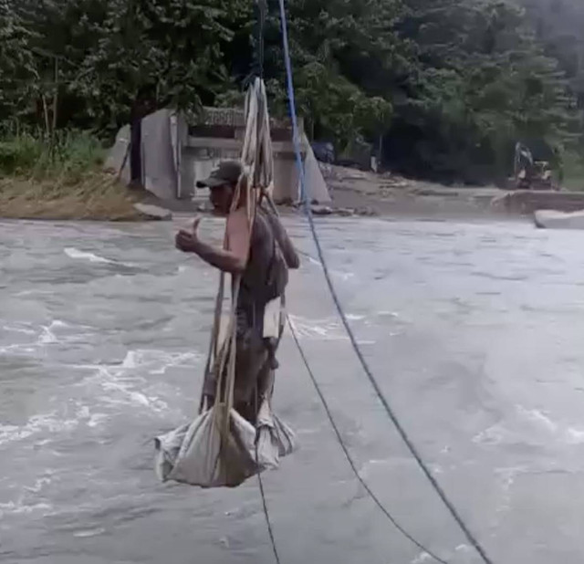 Warga melintasi sungai berarus deras menggunakan tali. Dok: Ist.