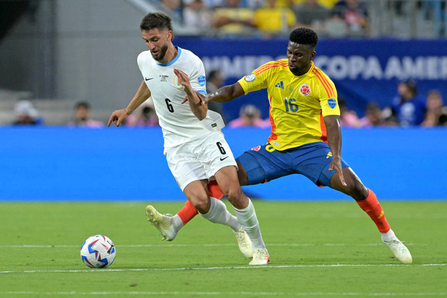 Rodrigo Bentancur duel dengan Jefferson Lerma saat Uruguay vs Kolombia dalam laga semifinal Copa America 2024 di Bank of America Stadium, Charlotte, Amerika Serikat, pada Kamis (11/7) pagi WIB. Foto: JUAN MABROMATA / AFP