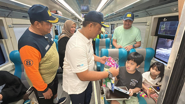 Membagikan suvenir kepada penumpang anak-anak.